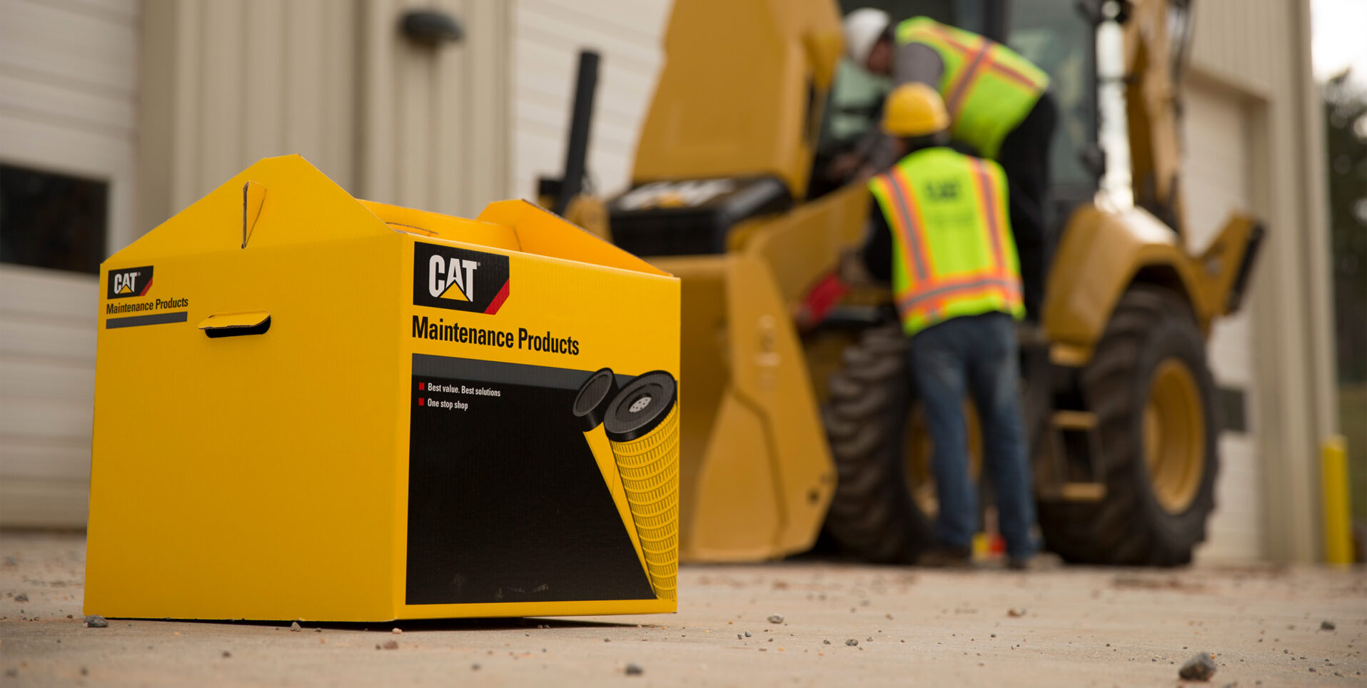Cat maintenance kit in the foreground with two men working on a Cat machine in the background